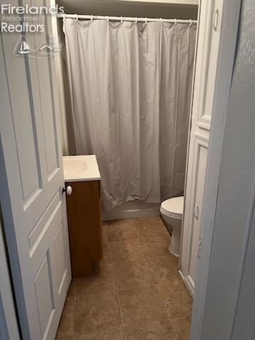 bathroom featuring curtained shower, vanity, and toilet