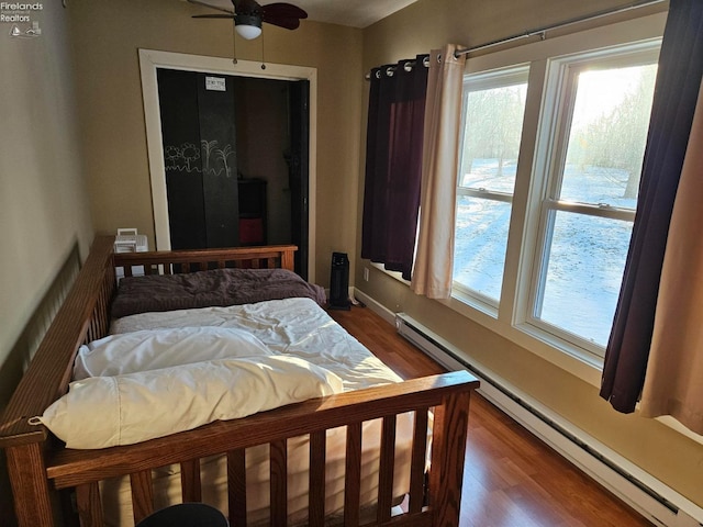 bedroom with a baseboard radiator, ceiling fan, and dark wood-type flooring