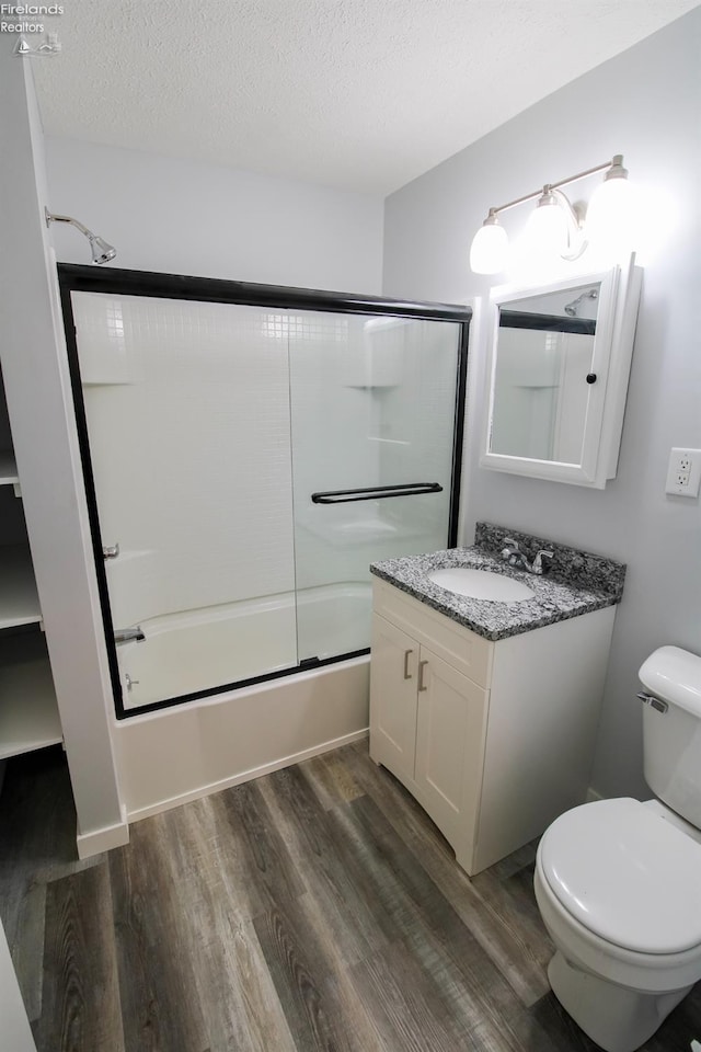 full bathroom with vanity, hardwood / wood-style flooring, toilet, enclosed tub / shower combo, and a textured ceiling