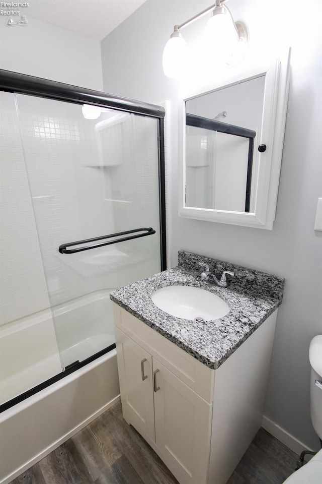 full bathroom featuring toilet, vanity, enclosed tub / shower combo, and hardwood / wood-style flooring