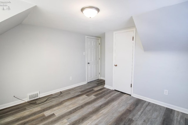 bonus room with dark hardwood / wood-style flooring and vaulted ceiling