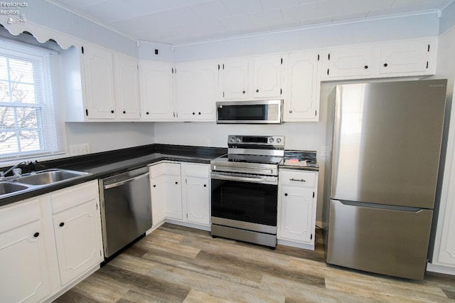 kitchen featuring white cabinets, crown molding, sink, light hardwood / wood-style floors, and stainless steel appliances