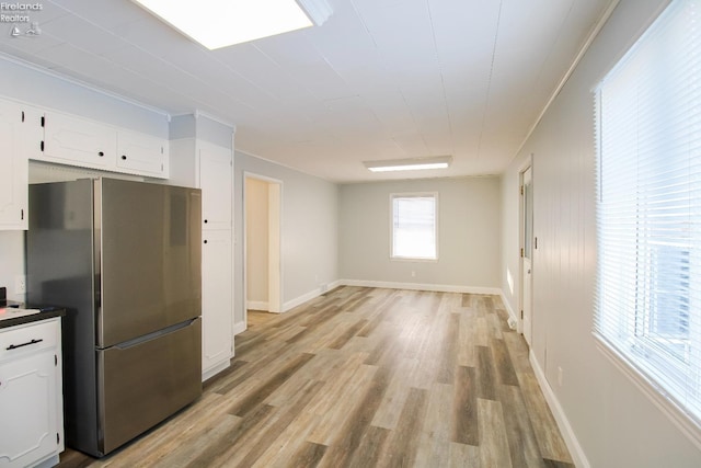 kitchen with stainless steel refrigerator, white cabinetry, and light wood-type flooring