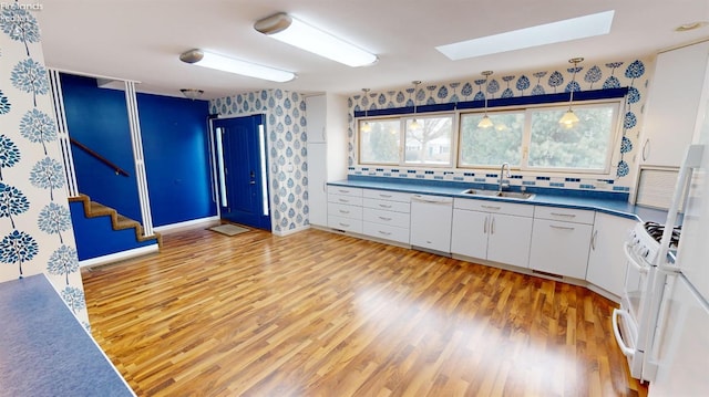 kitchen with white appliances, tasteful backsplash, white cabinetry, sink, and decorative light fixtures