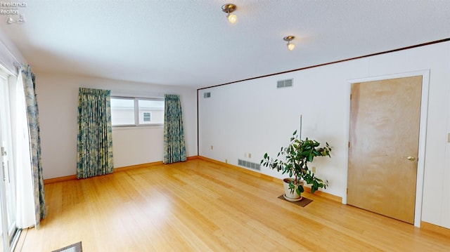 spare room with hardwood / wood-style floors and a textured ceiling