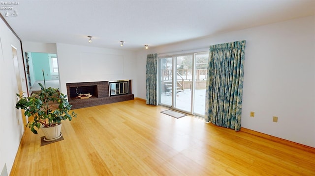 living room featuring a brick fireplace and wood-type flooring