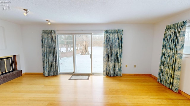 unfurnished living room featuring hardwood / wood-style flooring, a textured ceiling, and a fireplace