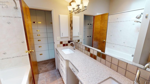 bathroom featuring tiled shower / bath, tile patterned floors, vanity, tasteful backsplash, and a notable chandelier