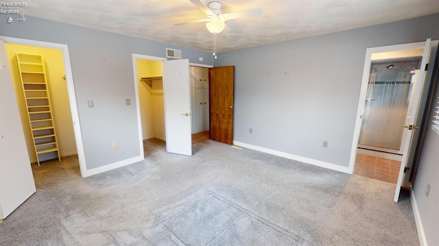 unfurnished bedroom with a spacious closet, a closet, light carpet, and ceiling fan