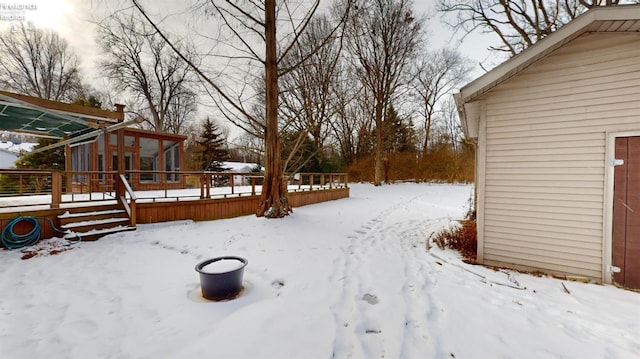 yard covered in snow with a sunroom and a wooden deck