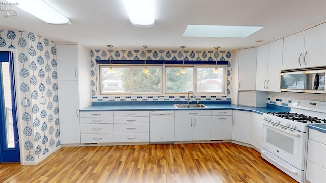 kitchen featuring sink, white appliances, white cabinets, and tasteful backsplash