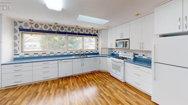 kitchen featuring sink, backsplash, white appliances, and white cabinetry