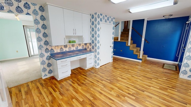 kitchen with built in desk, white cabinetry, and light hardwood / wood-style floors