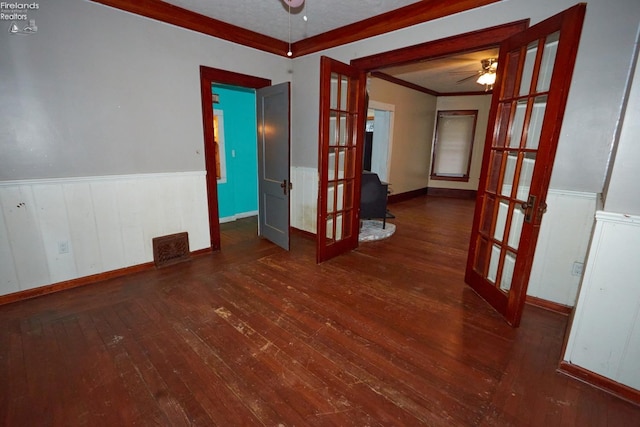 unfurnished room with french doors, crown molding, ceiling fan, and dark wood-type flooring