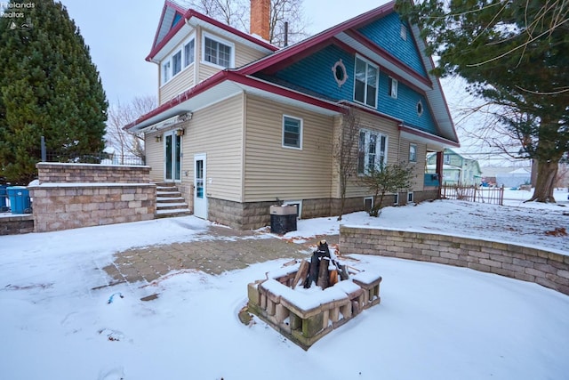 snow covered house with an outdoor fire pit