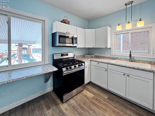 kitchen featuring pendant lighting, white cabinetry, stainless steel appliances, sink, and dark hardwood / wood-style floors