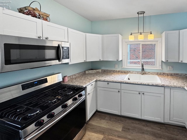 kitchen featuring stainless steel appliances, dark hardwood / wood-style flooring, hanging light fixtures, white cabinets, and sink