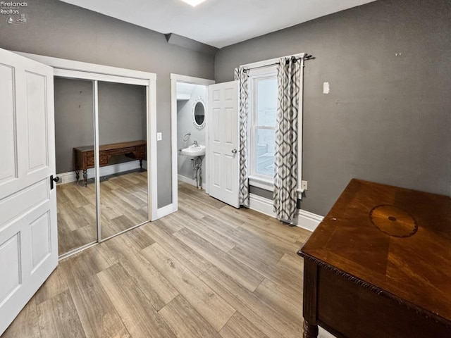 bedroom featuring ensuite bathroom, a closet, and light wood-type flooring