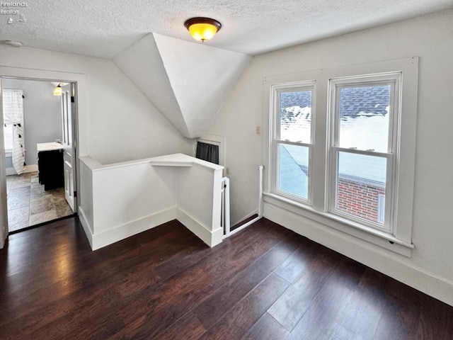 bonus room featuring a textured ceiling, dark wood-type flooring, and lofted ceiling