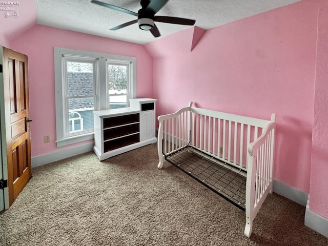 carpeted bedroom featuring a textured ceiling, ceiling fan, lofted ceiling, and a nursery area