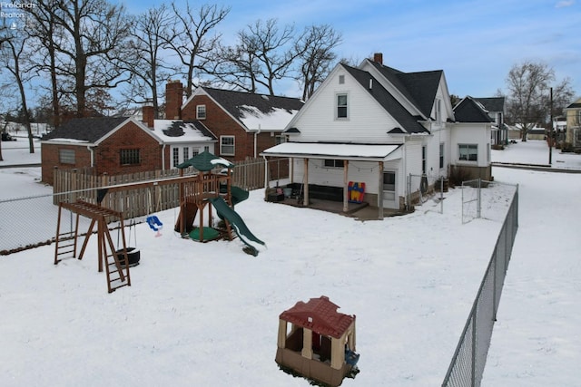 snow covered house featuring a playground