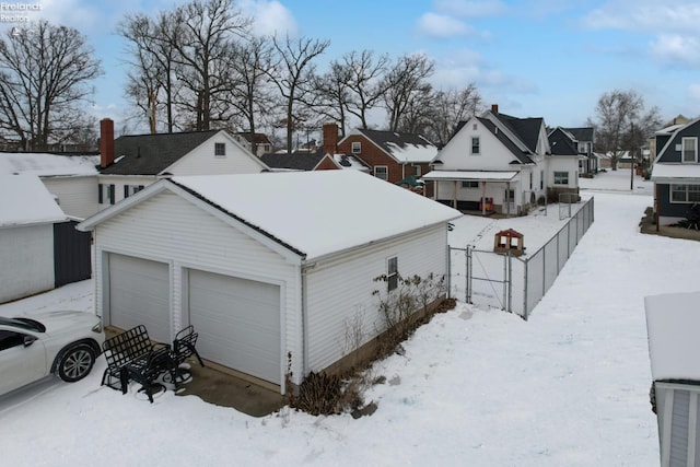 snow covered property with a garage and an outbuilding