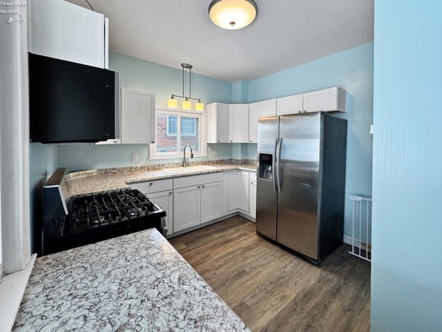 kitchen with black gas range, pendant lighting, sink, white cabinets, and stainless steel fridge