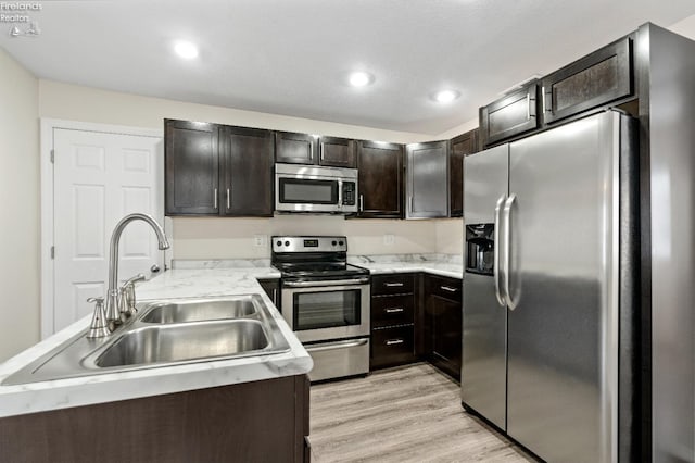 kitchen featuring dark brown cabinets, stainless steel appliances, light hardwood / wood-style floors, and sink