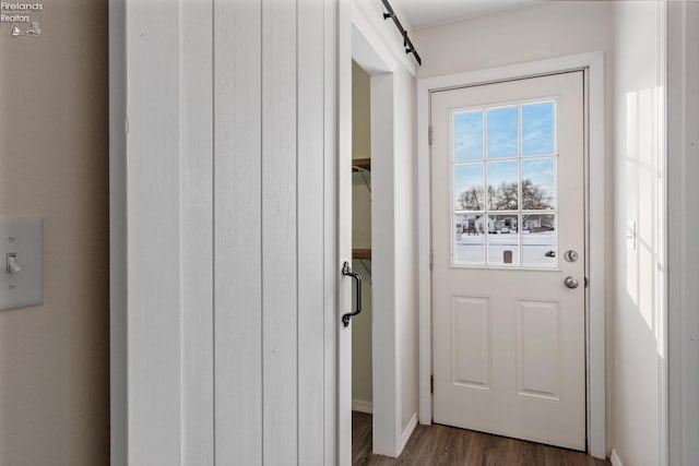 doorway to outside featuring a barn door and dark wood-type flooring