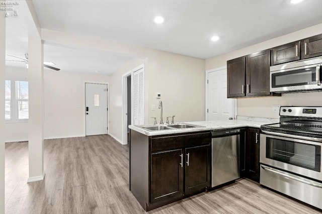 kitchen with light hardwood / wood-style floors, sink, kitchen peninsula, and stainless steel appliances