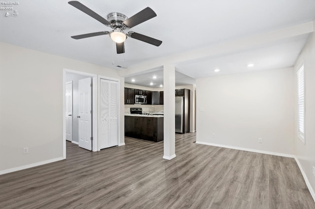 unfurnished living room featuring hardwood / wood-style flooring, ceiling fan, and sink