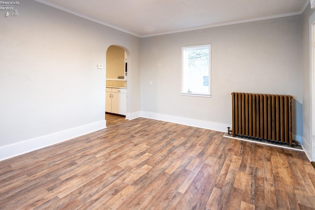 spare room with hardwood / wood-style floors, crown molding, and radiator heating unit