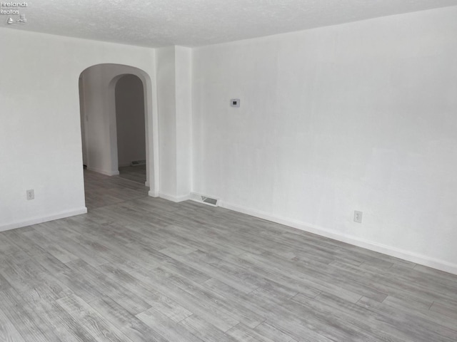 unfurnished room with a textured ceiling and light wood-type flooring