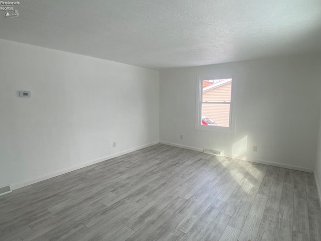 unfurnished room featuring a textured ceiling and hardwood / wood-style floors