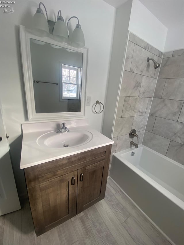 bathroom featuring tiled shower / bath and vanity