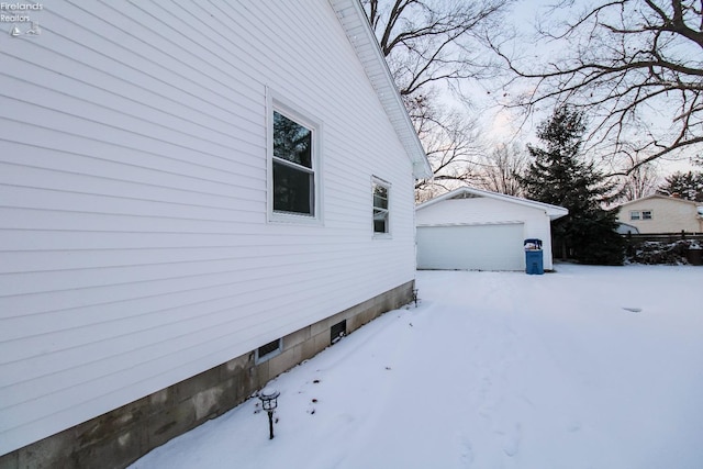 snow covered property with a garage and an outdoor structure