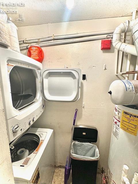 washroom with stacked washer and clothes dryer and water heater