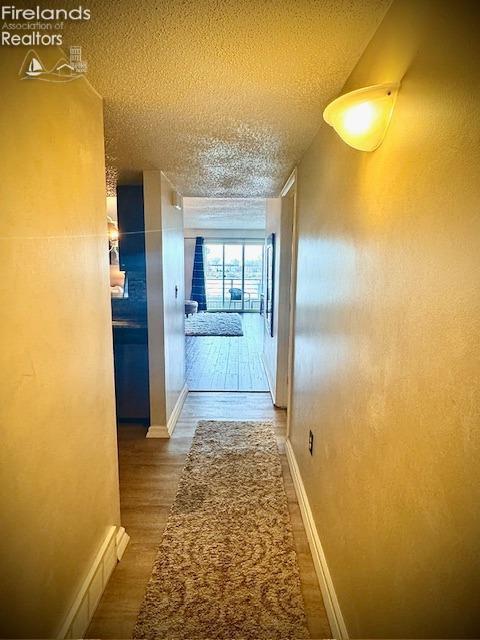 hallway featuring a textured ceiling and hardwood / wood-style flooring