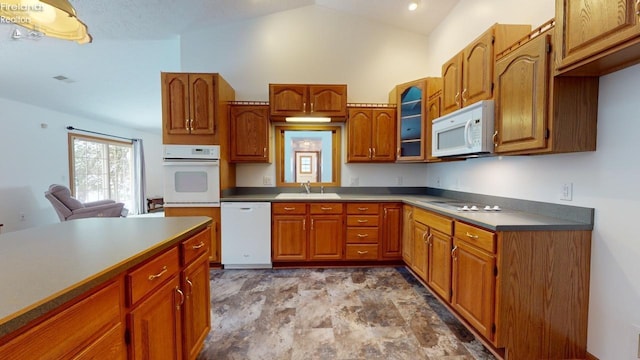 kitchen with white appliances, lofted ceiling, and sink