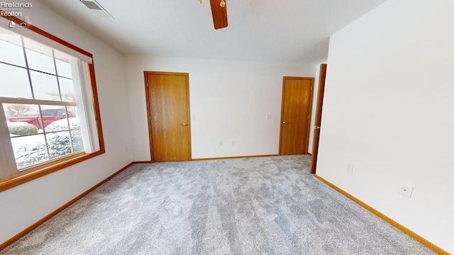 carpeted spare room featuring ceiling fan