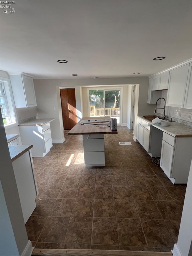 kitchen with decorative backsplash, sink, white cabinetry, and a center island