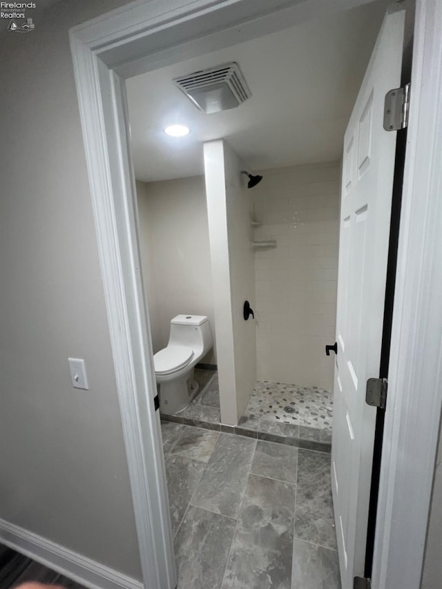 bathroom with toilet and tiled shower