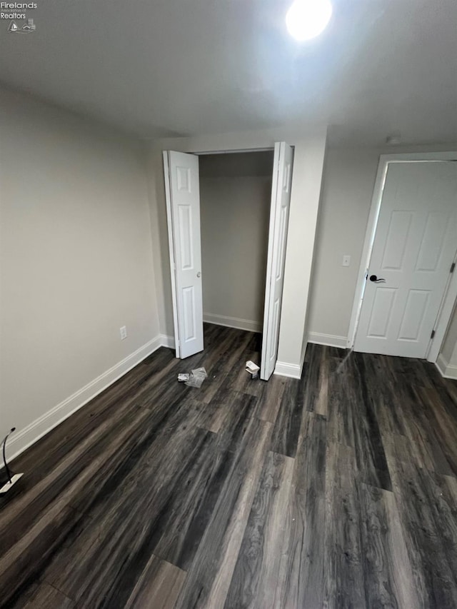 unfurnished bedroom featuring a closet and dark hardwood / wood-style flooring