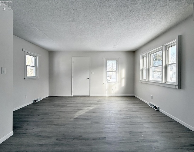 unfurnished room with a textured ceiling and dark hardwood / wood-style flooring