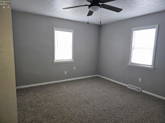 empty room with ceiling fan, a wealth of natural light, and carpet floors