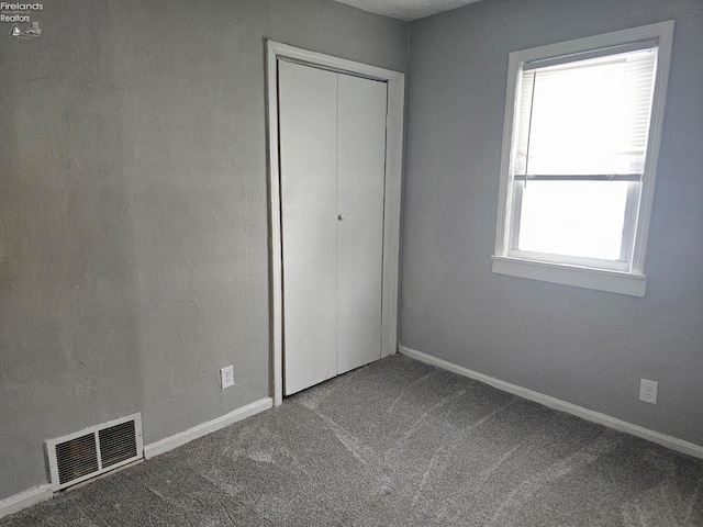 unfurnished bedroom featuring carpet floors, a closet, and multiple windows