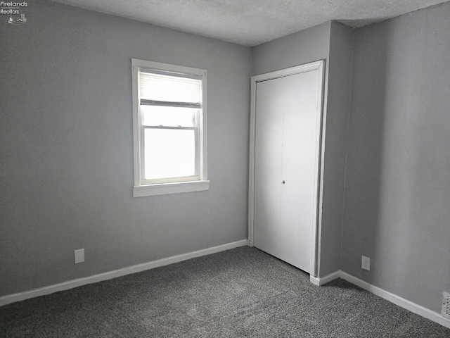 unfurnished bedroom with a textured ceiling and carpet floors