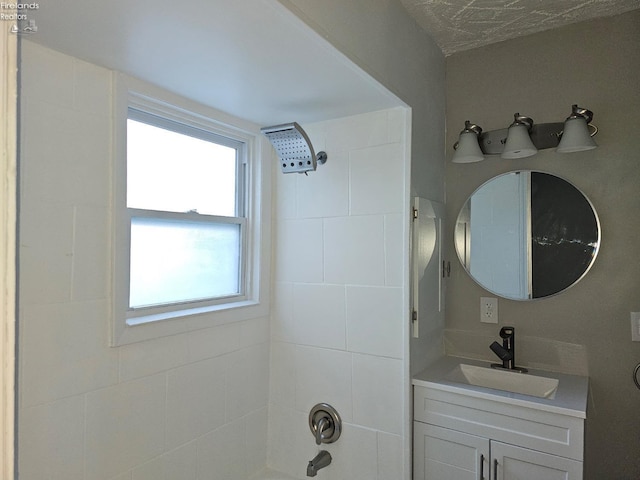 bathroom with tiled shower / bath combo and vanity