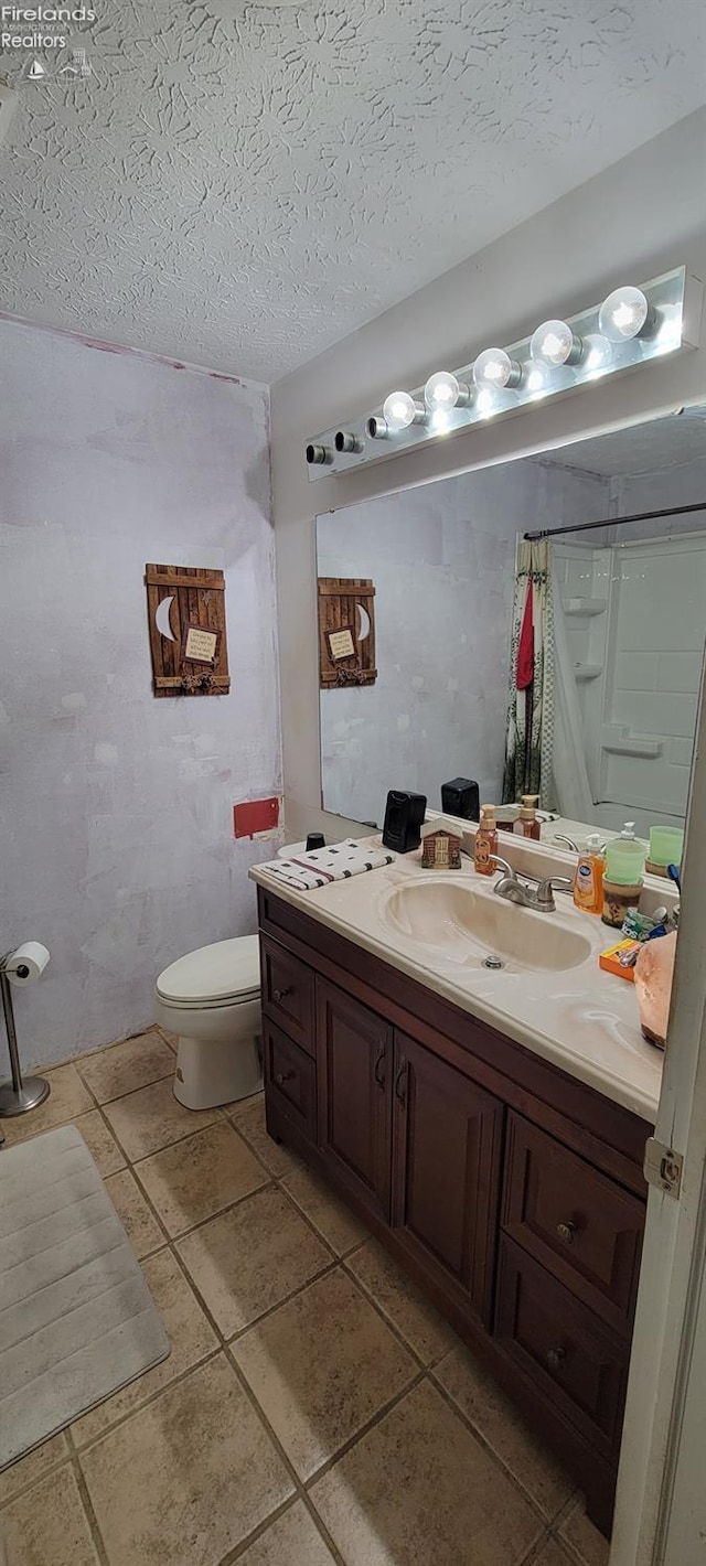 bathroom featuring toilet, vanity, walk in shower, and a textured ceiling