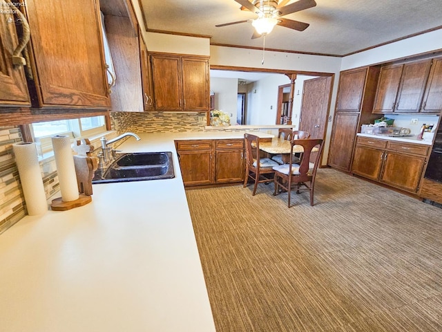 kitchen with ceiling fan, backsplash, a textured ceiling, crown molding, and sink